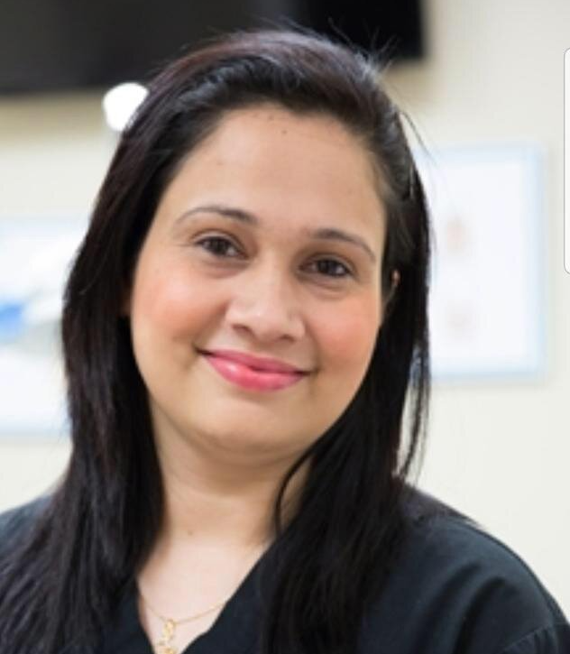 A woman wearing a black scrub top smiles for the camera