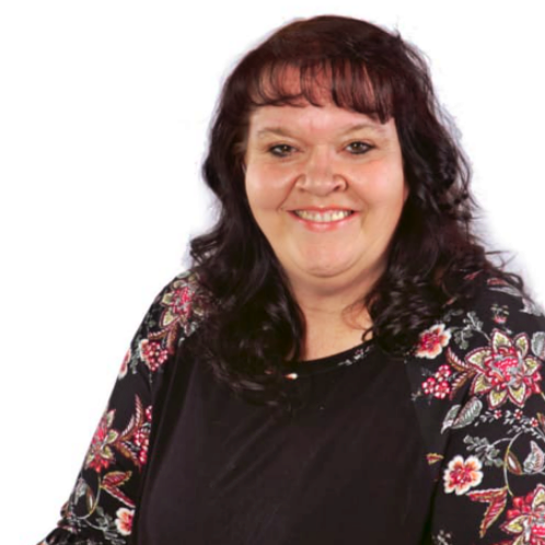 Smiling woman with dark hair wearing a black top and floral cardigan on a white background