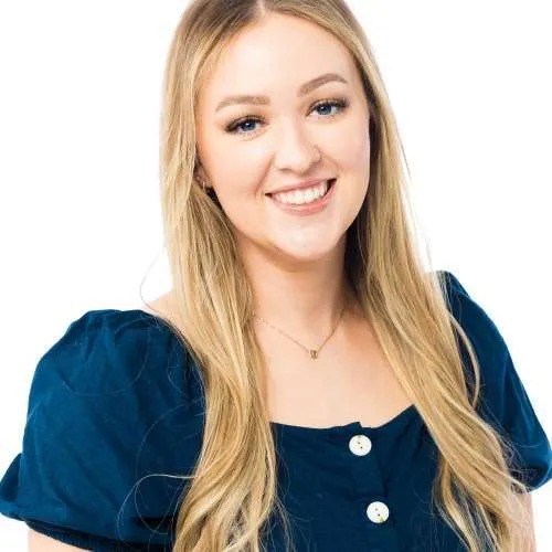 Smiling blonde woman in a navy blue top against a white background