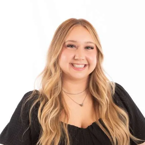 Smiling woman with long blonde hair wearing a black top on a white background