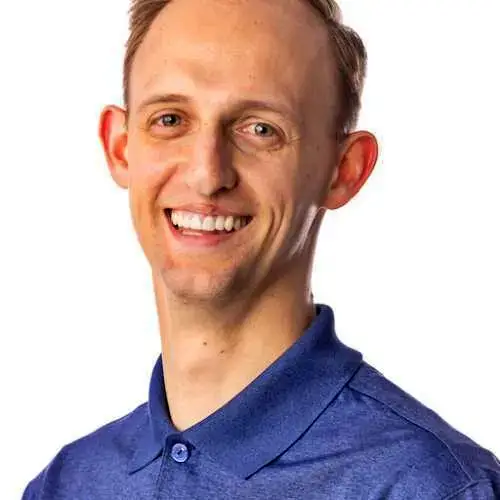 Smiling man in a blue collared shirt against a white background