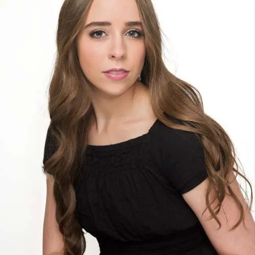 Portrait of a woman with long brown hair wearing a black top against a white background