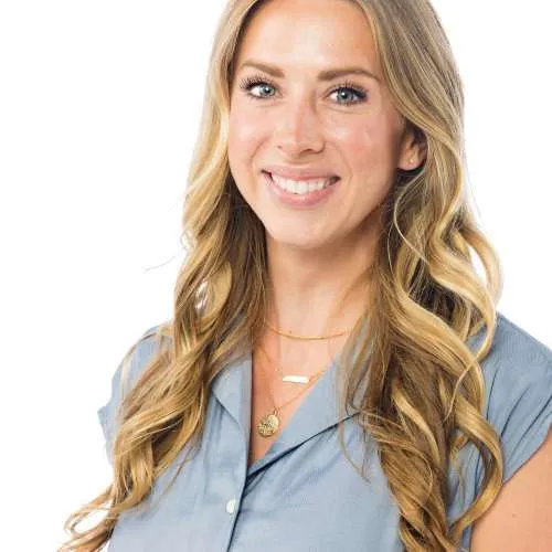 Smiling blonde woman in a light blue blouse against a white background
