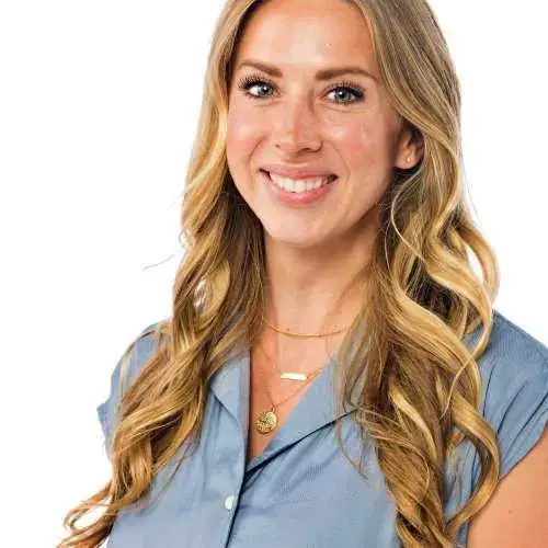 Smiling blonde woman in a light blue blouse against a white background