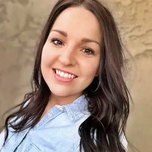 Smiling woman with dark hair in a light blue shirt against a beige background
