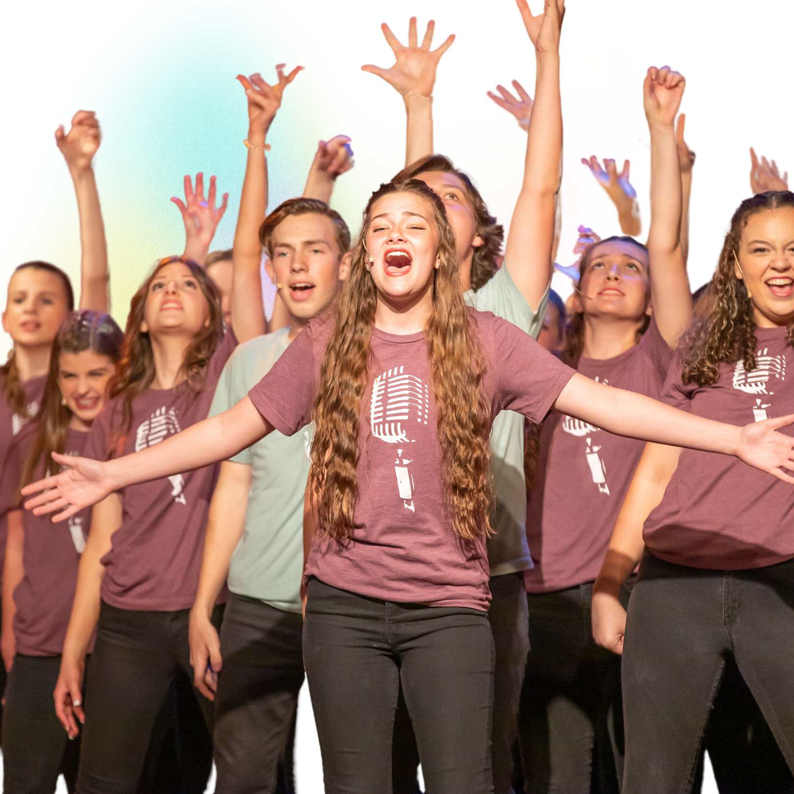 Group of people in maroon shirts singing with arms raised onstage