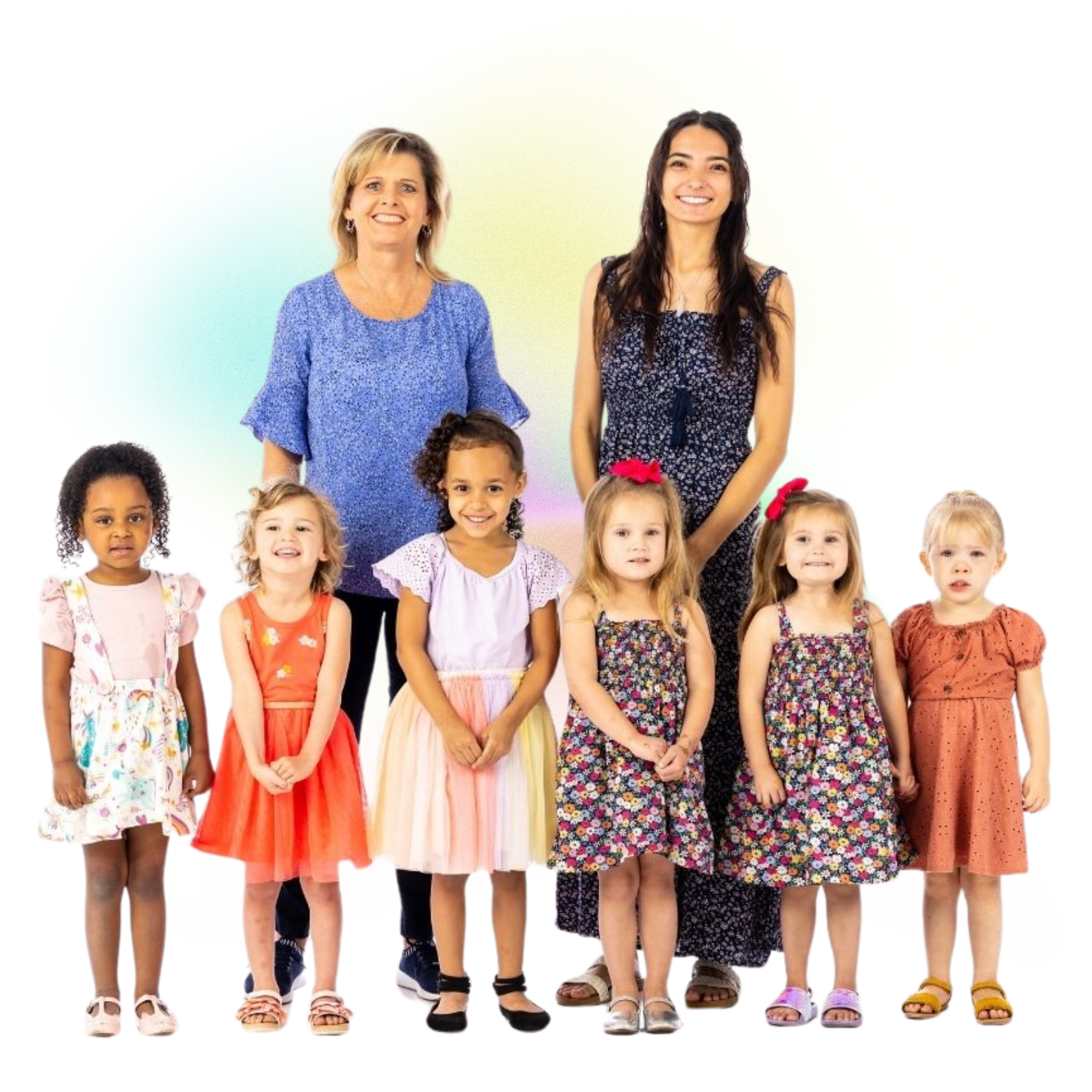 Seven children and two women standing together against a white background, dressed in colorful clothes