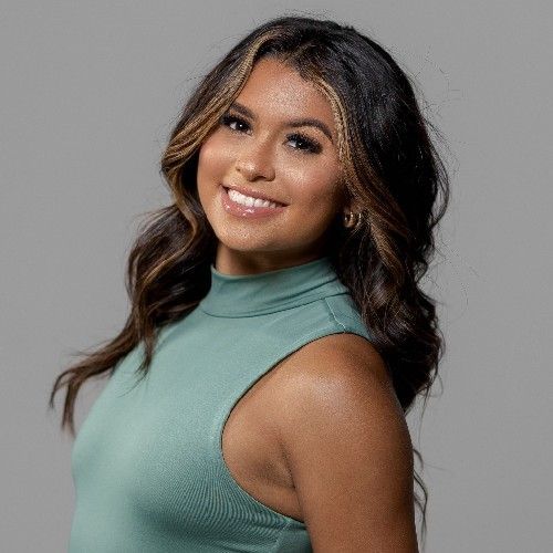 Smiling woman in a teal sleeveless top against a gray background