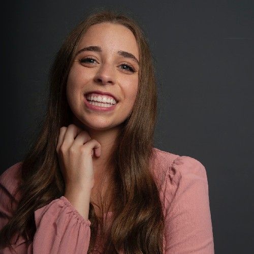 Smiling woman in a pink blouse posing against a dark background