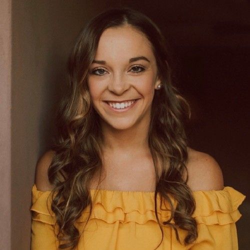 Smiling woman in a yellow off-shoulder top against a dark background