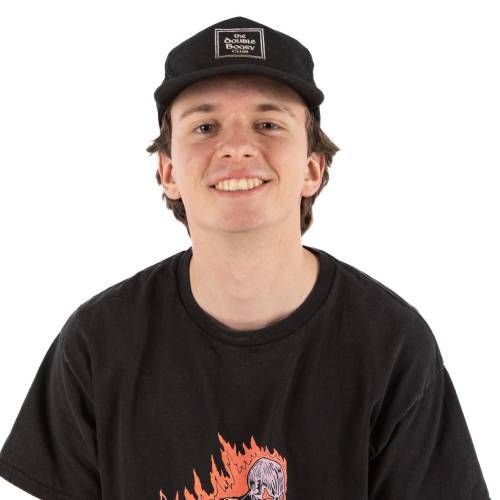 Smiling person in a black cap and black graphic T-shirt against a white background