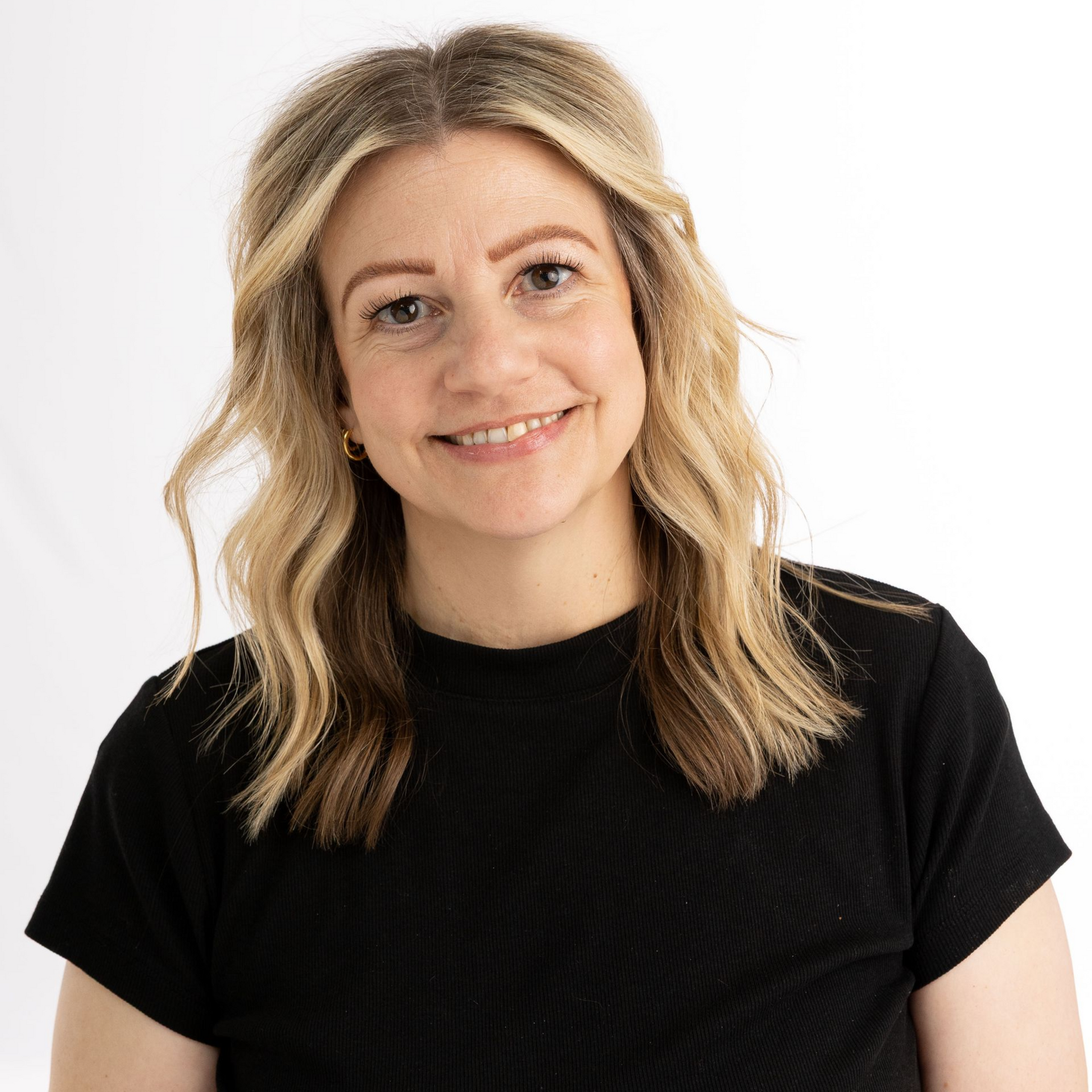Smiling person with blonde hair wearing a black shirt against a white background