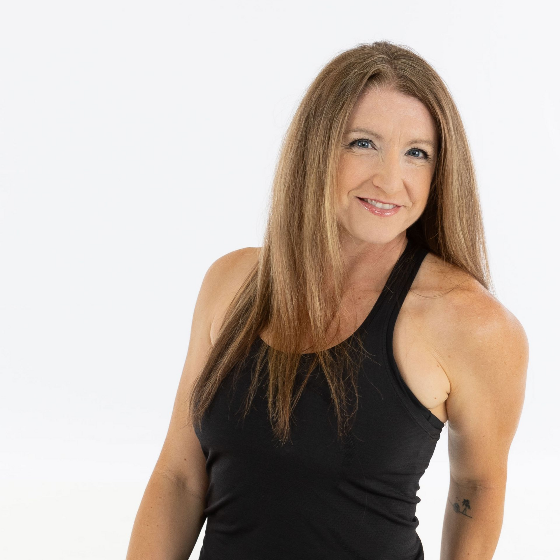 Smiling person in a black sleeveless top against a white background