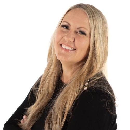 Smiling blonde woman in a black top with arms crossed against a white background