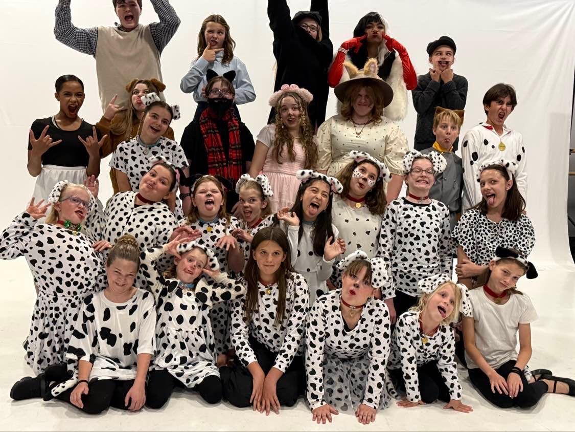 Group of children in black-and-white dalmatian costumes posing on a white backdrop