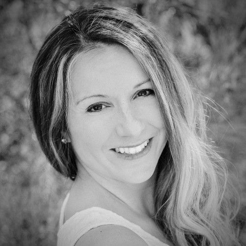 Smiling person with long hair in a black-and-white portrait outdoors