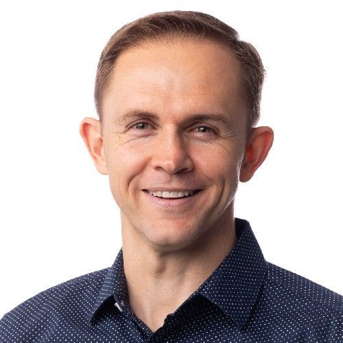Smiling man in a navy dotted shirt against a white background