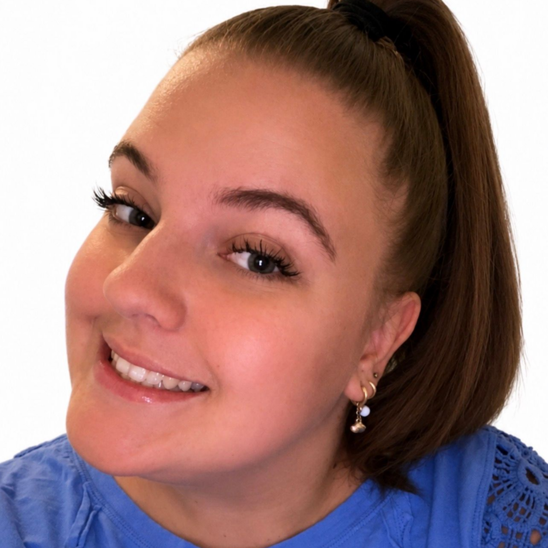 Smiling person with long hair wearing a bright pink shirt against a white background