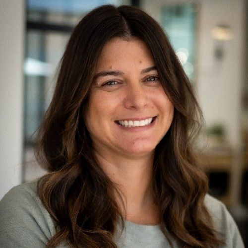 Smiling woman with long brown hair in a softly lit indoor office setting