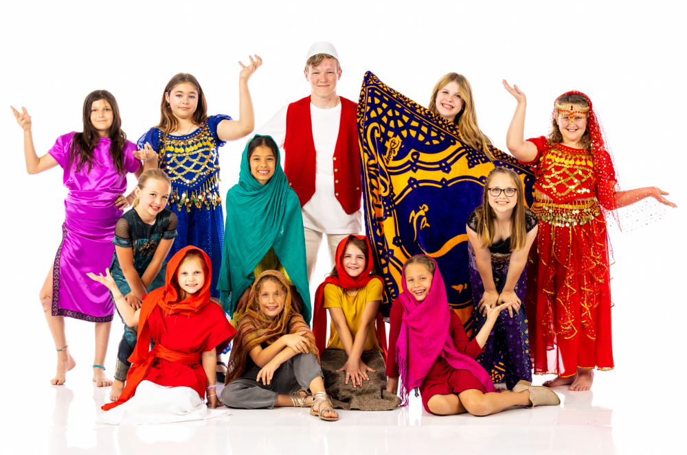 Group of children posing in colorful costumes against a white background