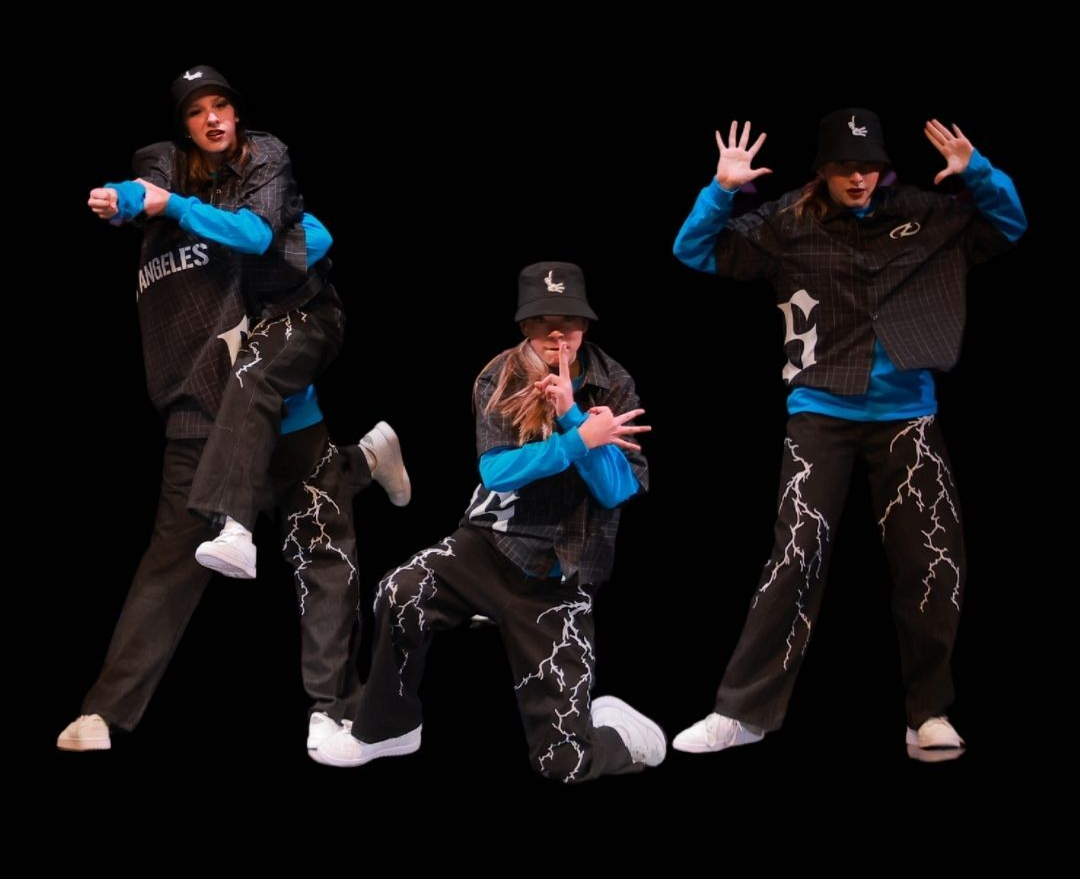 Three dancers posing in black outfits with blue sleeves against a black background