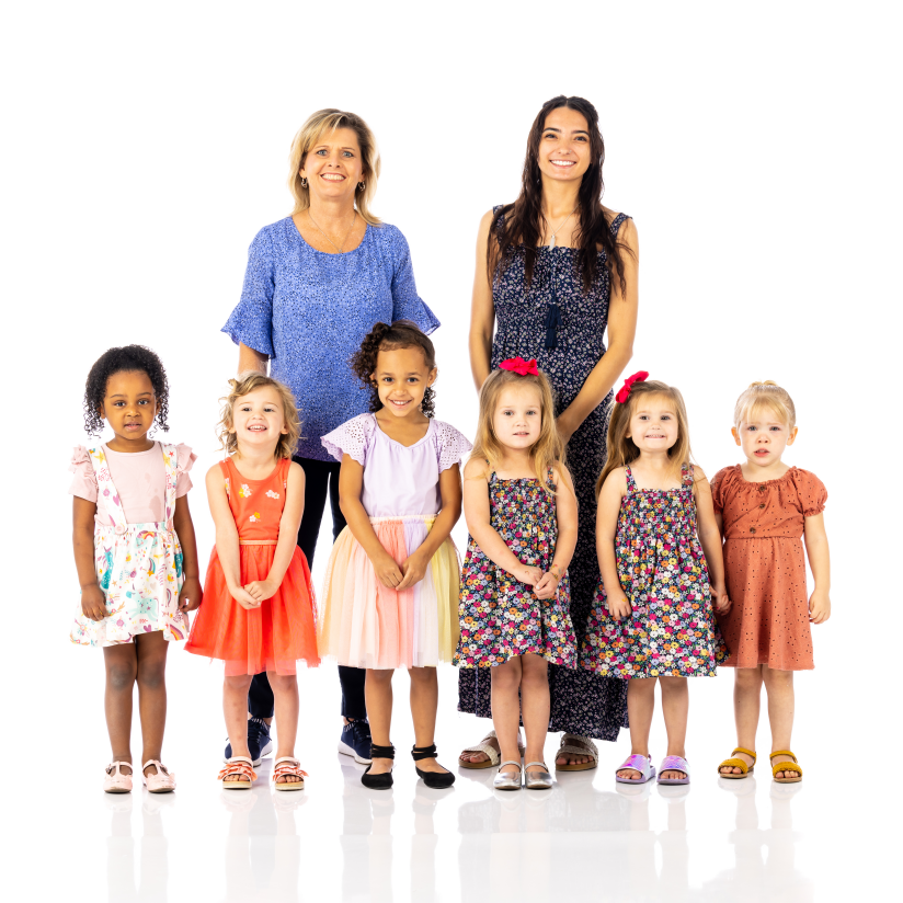 Two women standing behind six children posing in colorful clothes on a white background