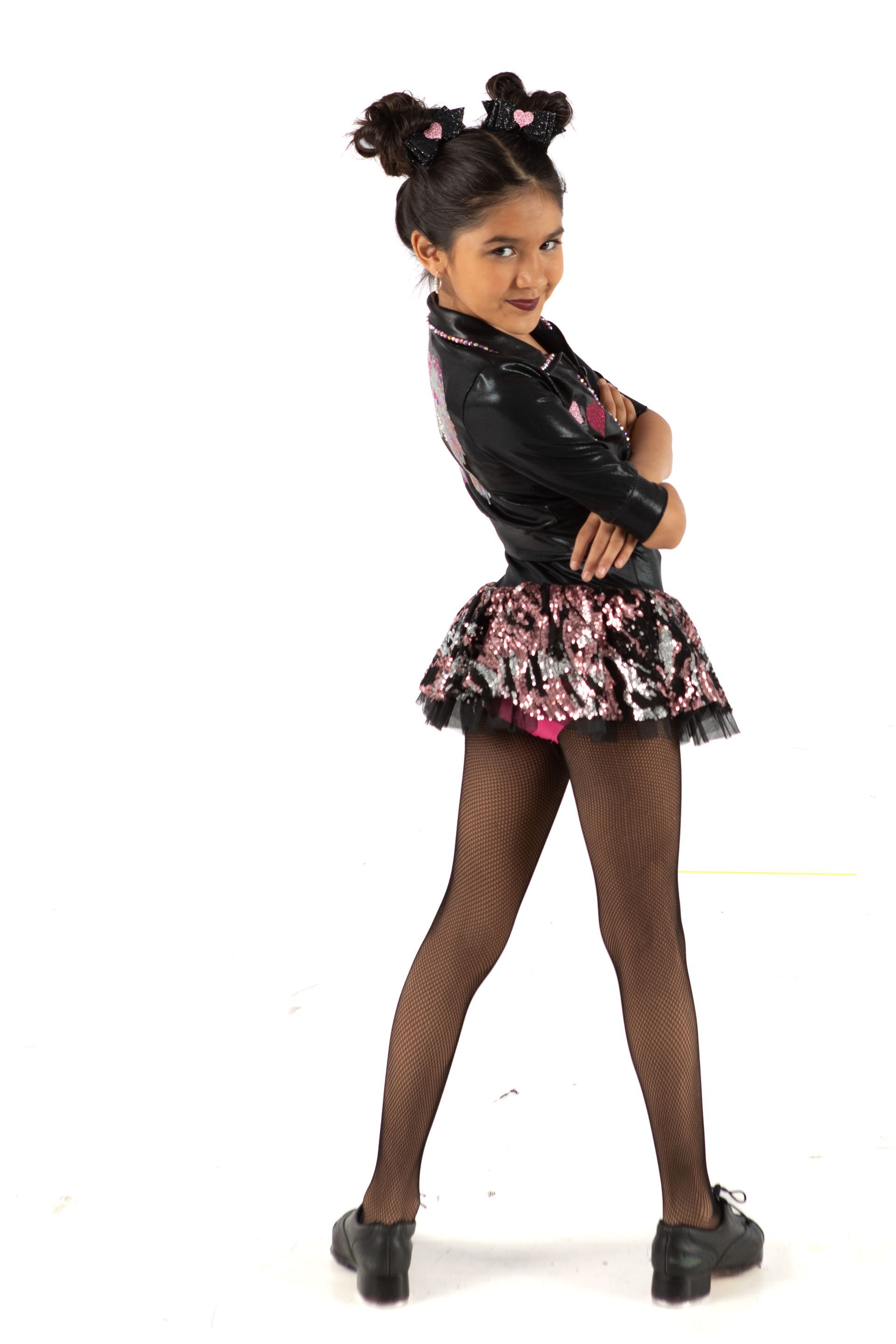 Woman posing in a black and pink outfit with fishnet tights, standing against a white background
