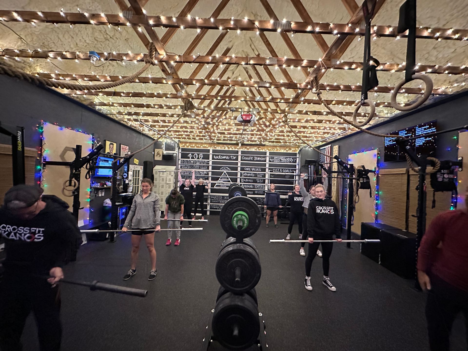 People training in a gym in Marietta, GA with weights, mirrors, and string lights overhead.