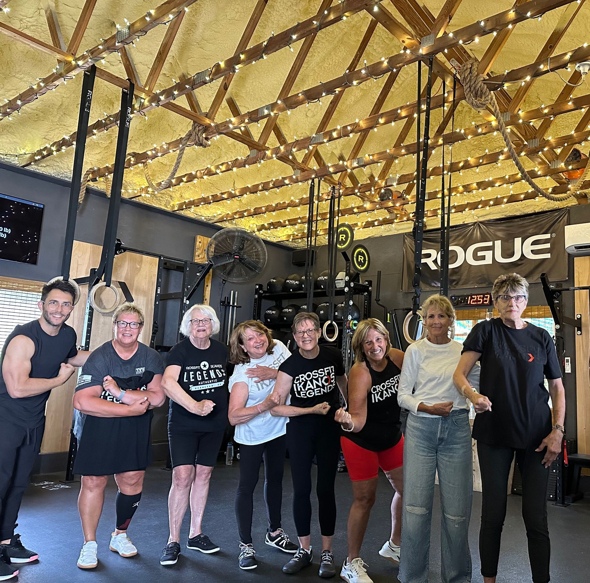 Group of people posing in a gym in Marietta, GA with Rogue equipment and exposed wooden ceiling rafters