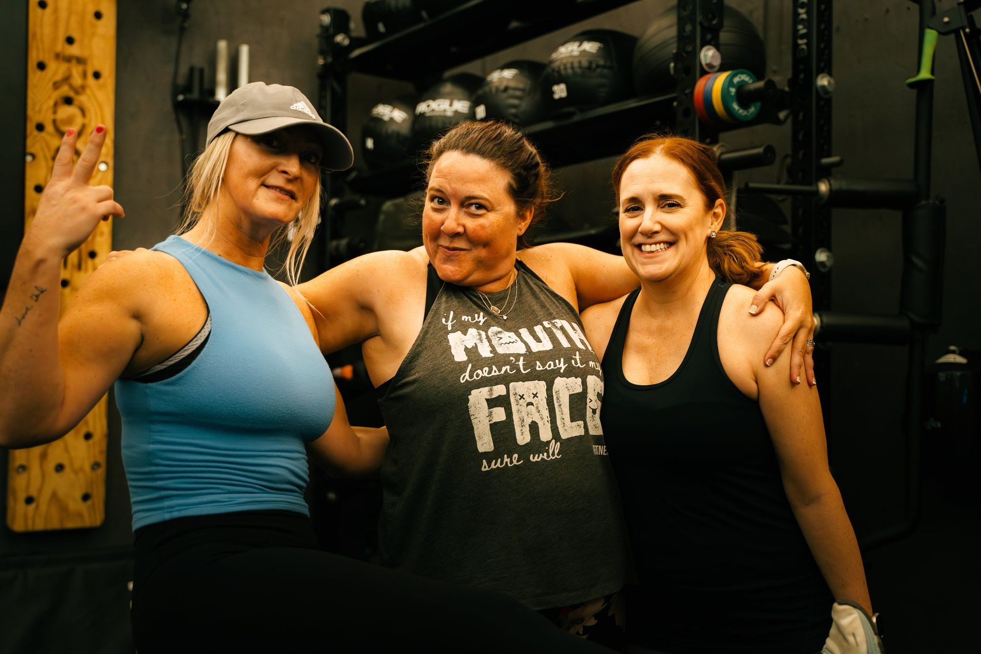 Three friends posing together in a gym in Kennesaw, GA, smiling and flexing after a workout.
