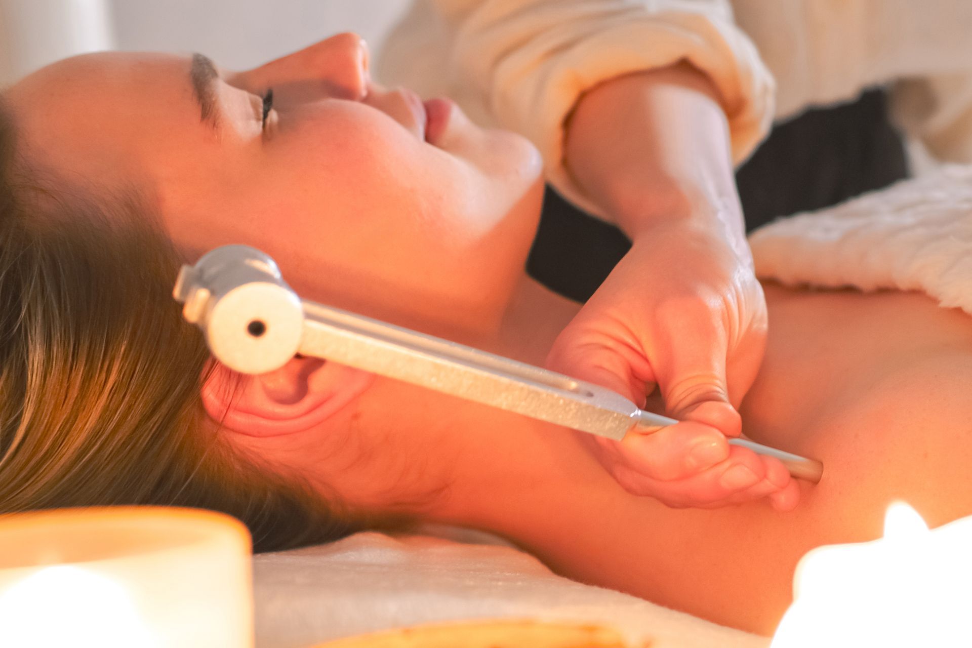 A woman is getting a healing massage with her eyes closed.