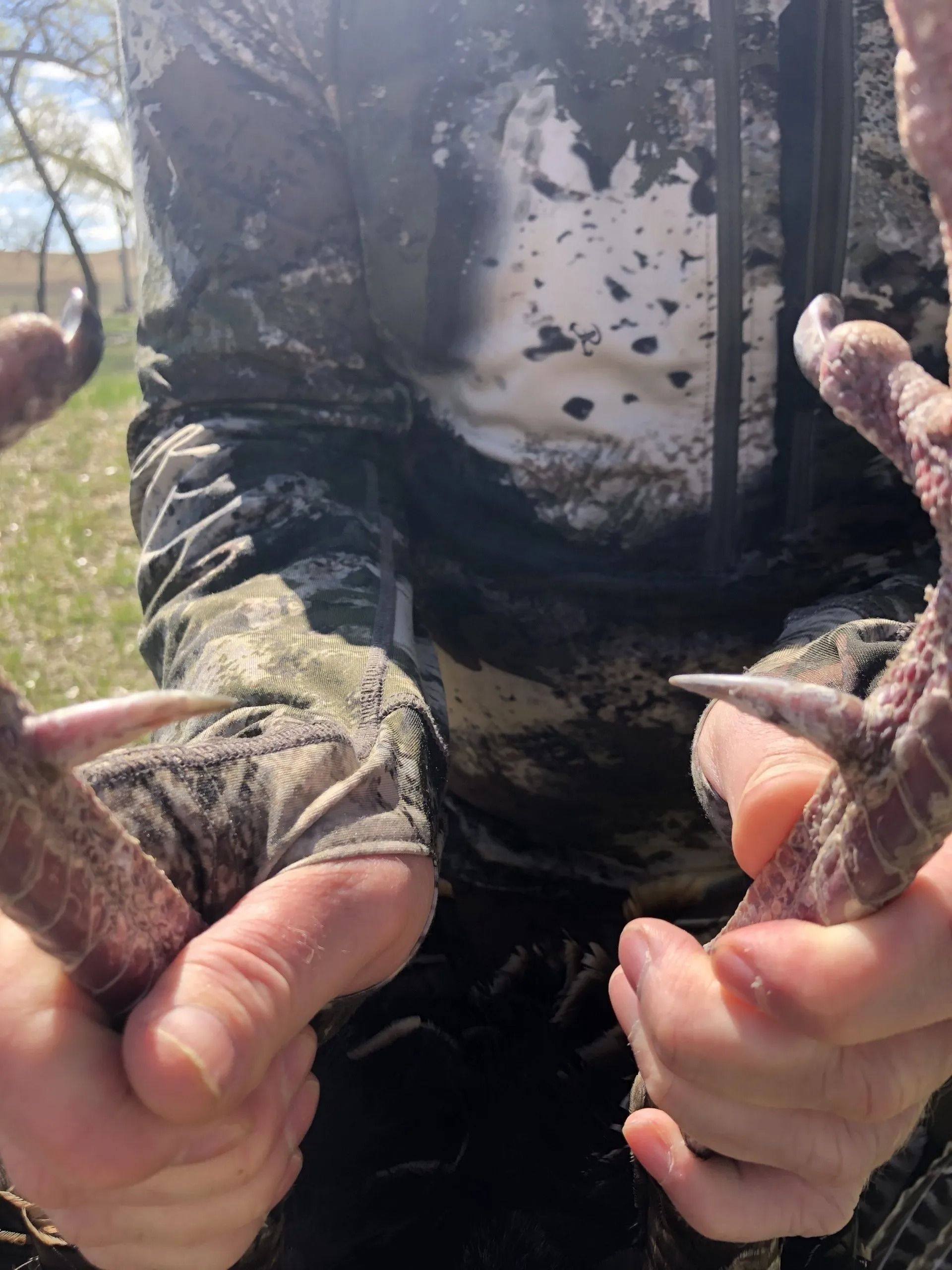 Hands holding two muddy fish close to the camera outdoors