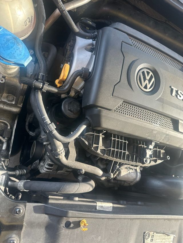 Volkswagen TSI engine compartment, black engine cover, various hoses and components visible.| Jimmy's German Auto Repair