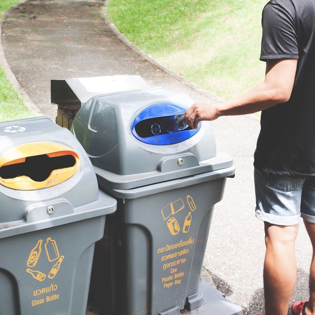 man throwing a plastic bottle into the recycle trash can