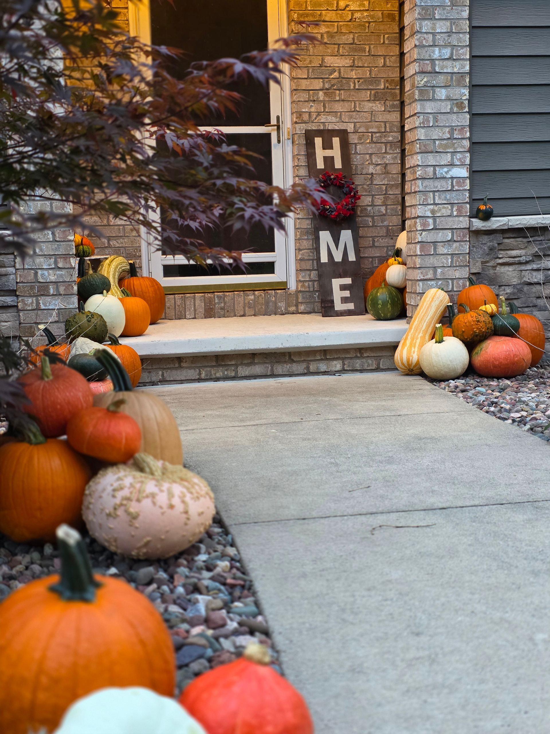 A front porch decorated with pumpkins and gourds for autumn, with a