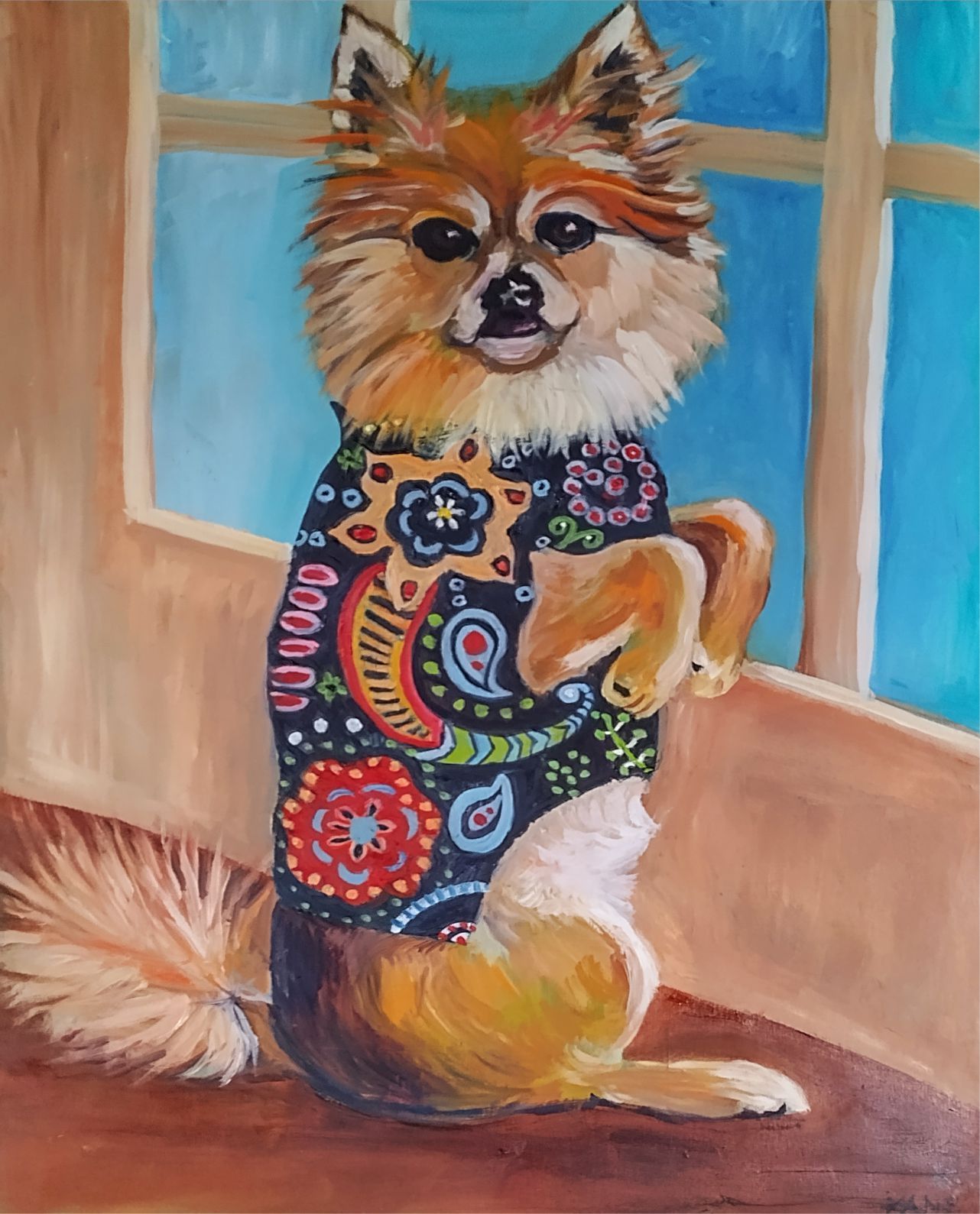 Fluffy dog in a colorful patterned sweater sitting by a window on a wooden floor