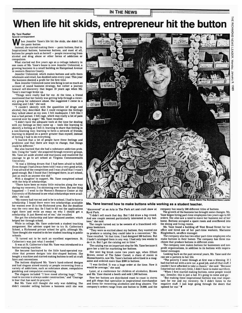 Woman smiling, surrounded by buttons. She's holding a pile.