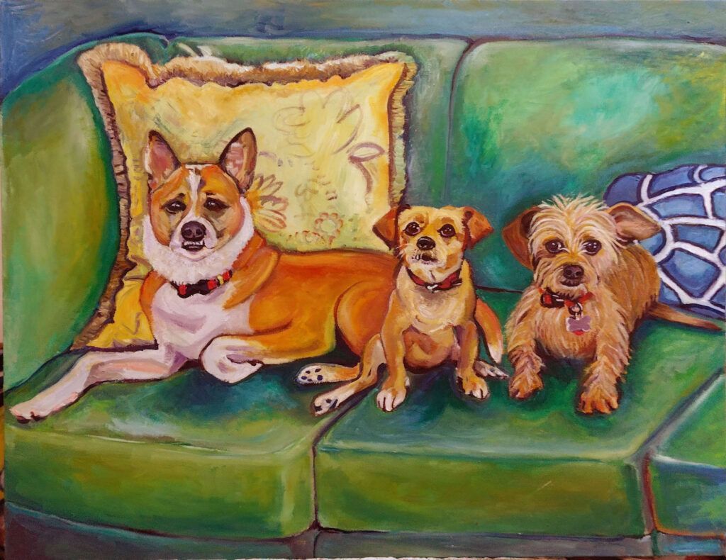 Three dogs, brown and tan, relax on a green couch with pillows.