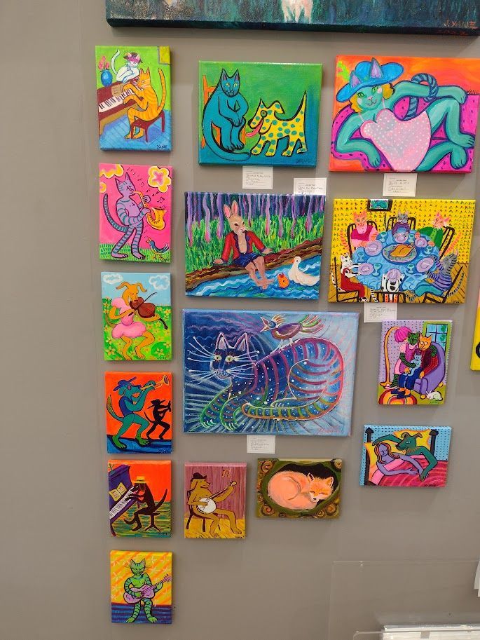 Colorful cartoon paintings of quirky animal characters on a gallery wall.