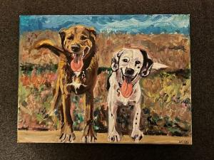 Two dogs, one brown and one dalmatian, happily pose outdoors, tongues out.
