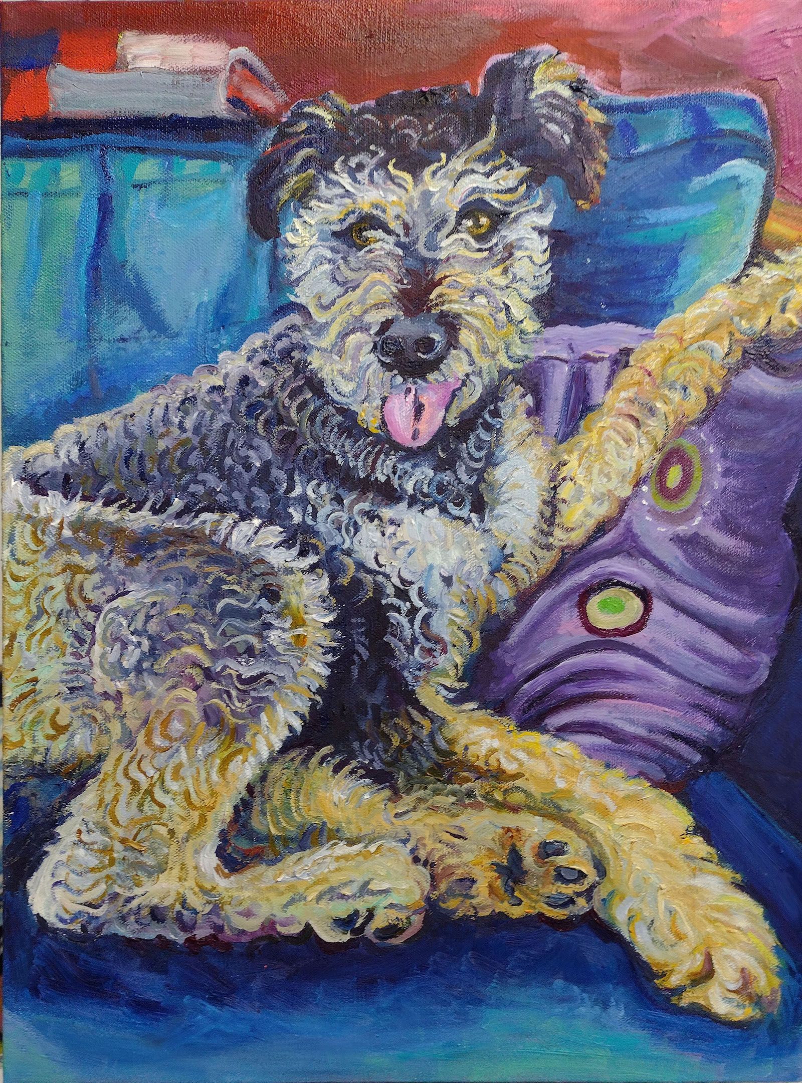 Dog with tongue out, lounging on a blue couch, resting on a purple pillow.