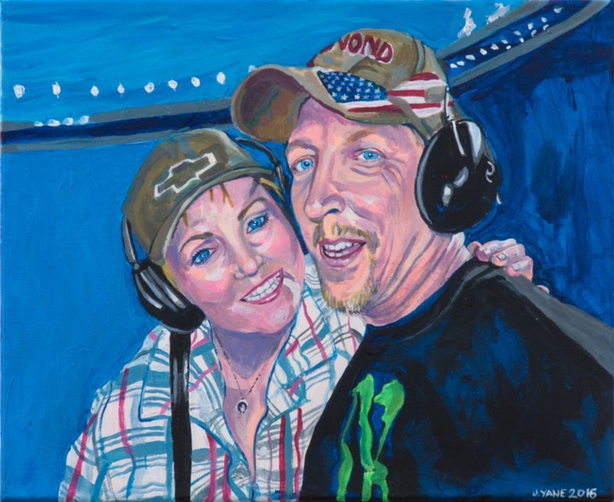 Couple smiling, wearing headphones and hats, possibly at an event with blue and white lights.