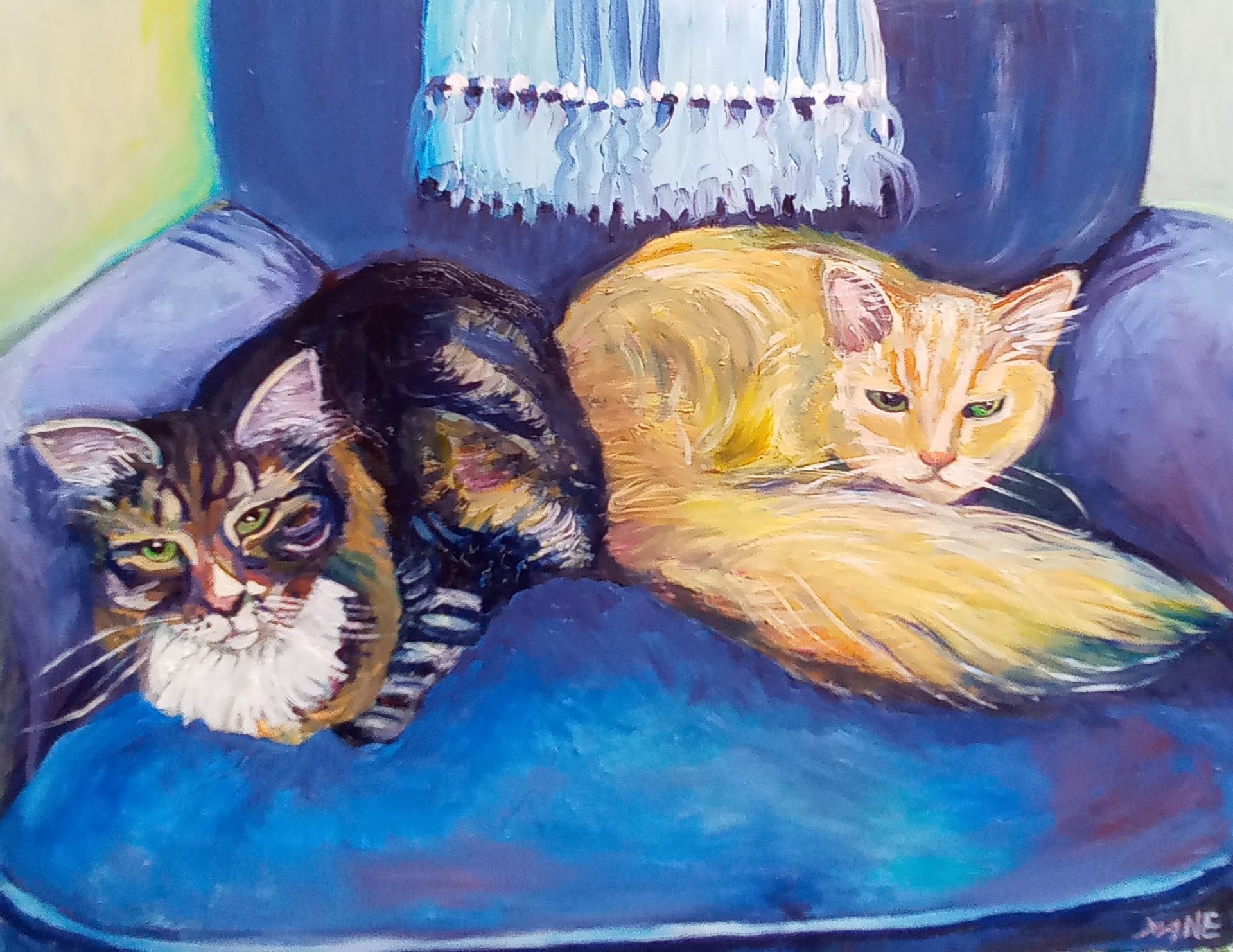 Two cats, one black and brown, one orange, curled up on a blue armchair under a blue fringe.
