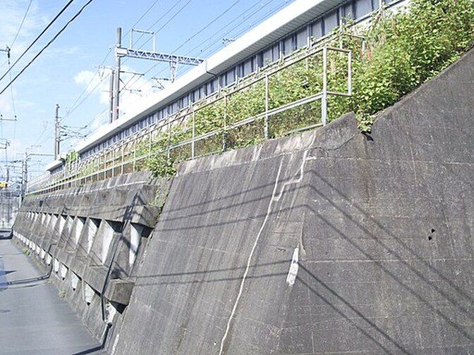 A concrete wall with a railing and a building in the background