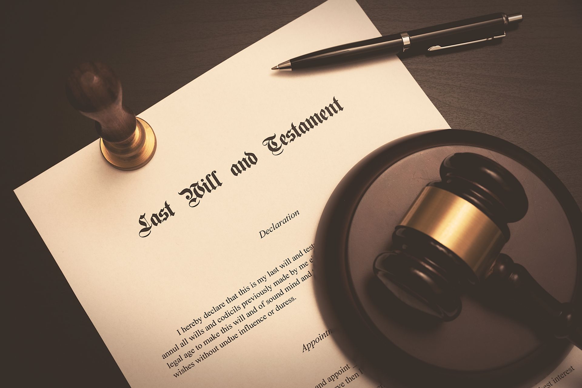 Last will and testament document with a gavel, stamp, and pen on a desk. Last will and testament document with a gavel, stamp, and pen on a desk.