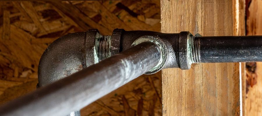 A close-up of a pipe connected to a wooden wall.
