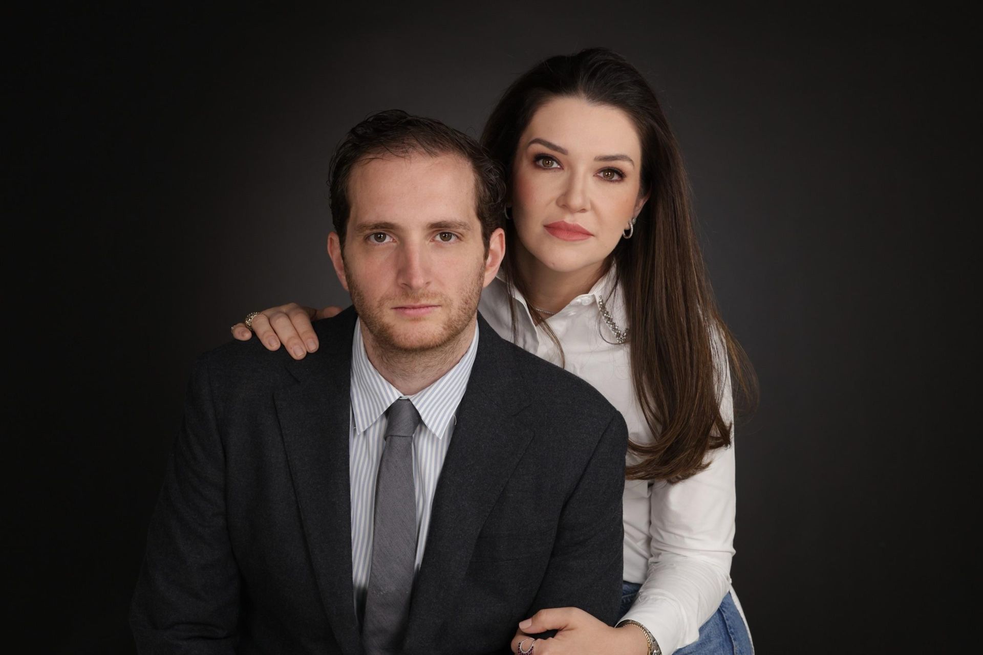 Um homem de terno e gravata e uma mulher de camisa branca estão posando para uma foto.