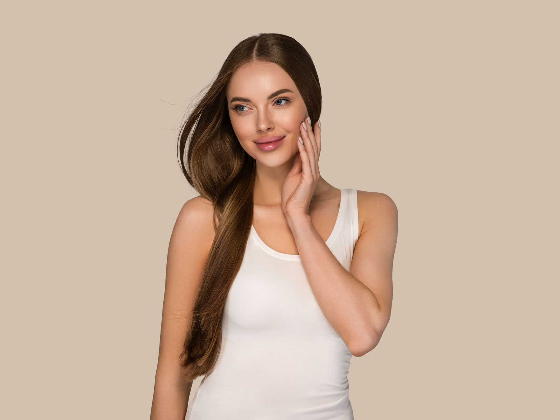 Uma mulher de blusa branca está tocando o rosto e sorrindo.