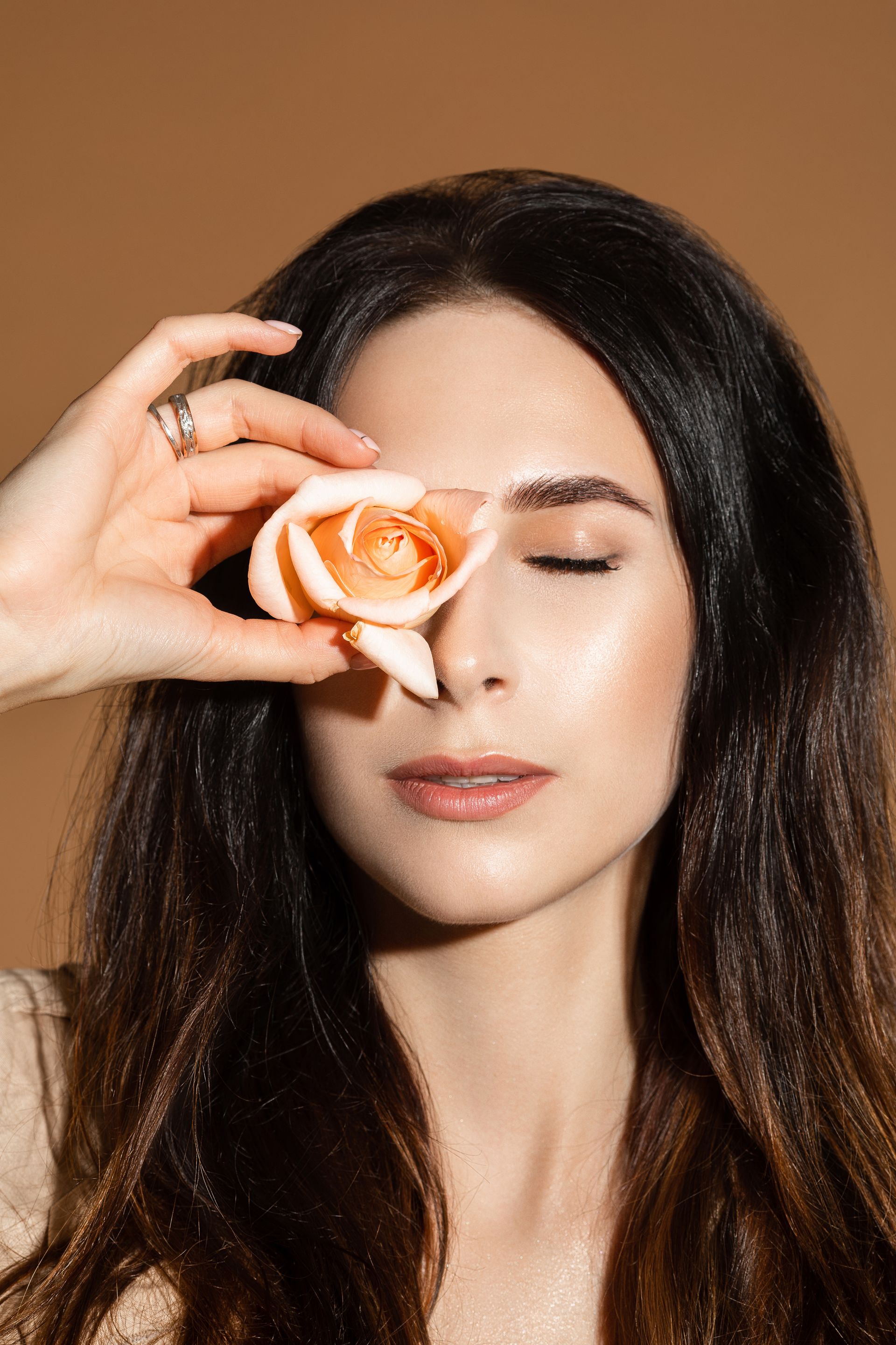 Uma mulher está segurando uma rosa na frente dos olhos.