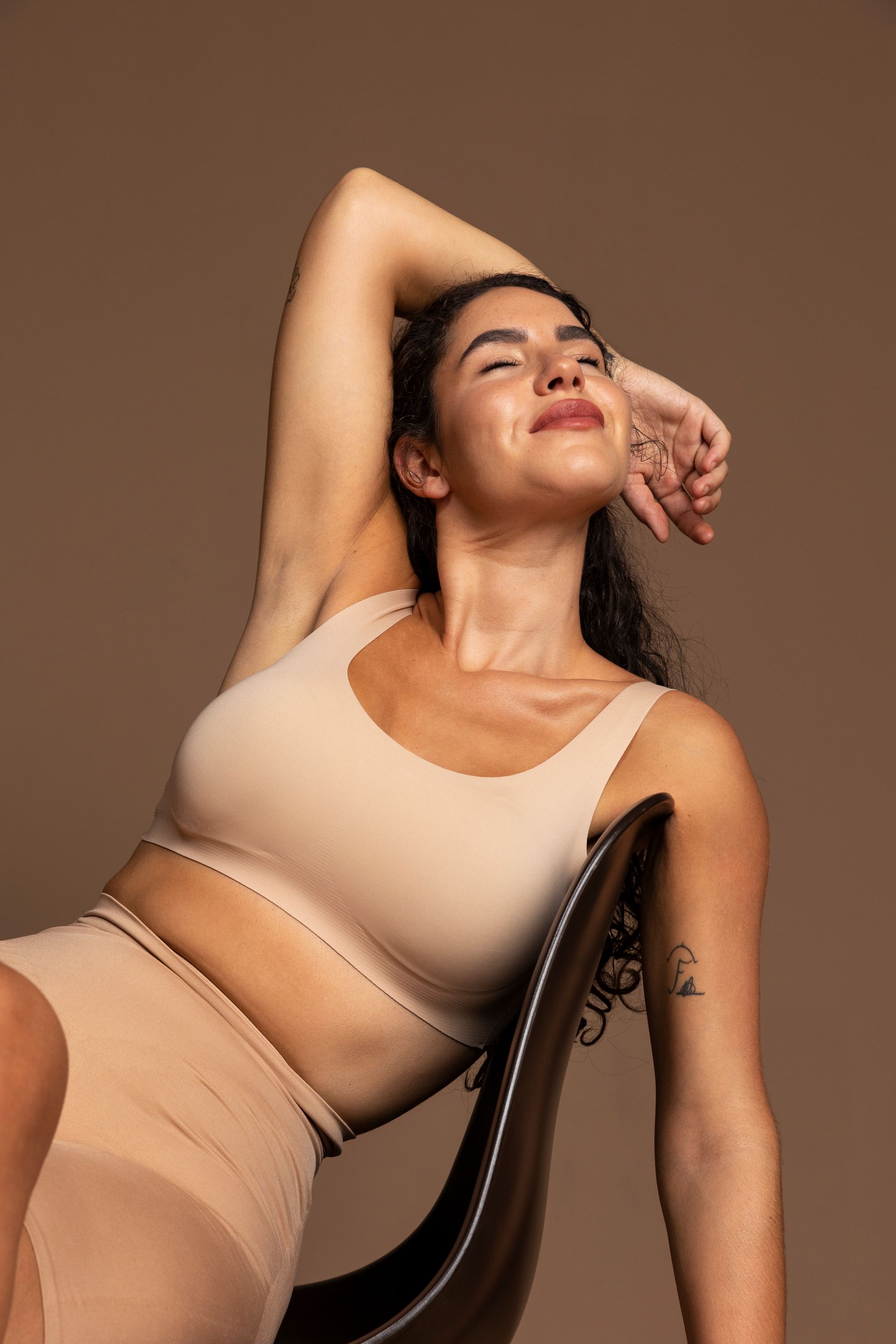 Uma mulher está sentada em uma cadeira com a cabeça apoiada na mão.